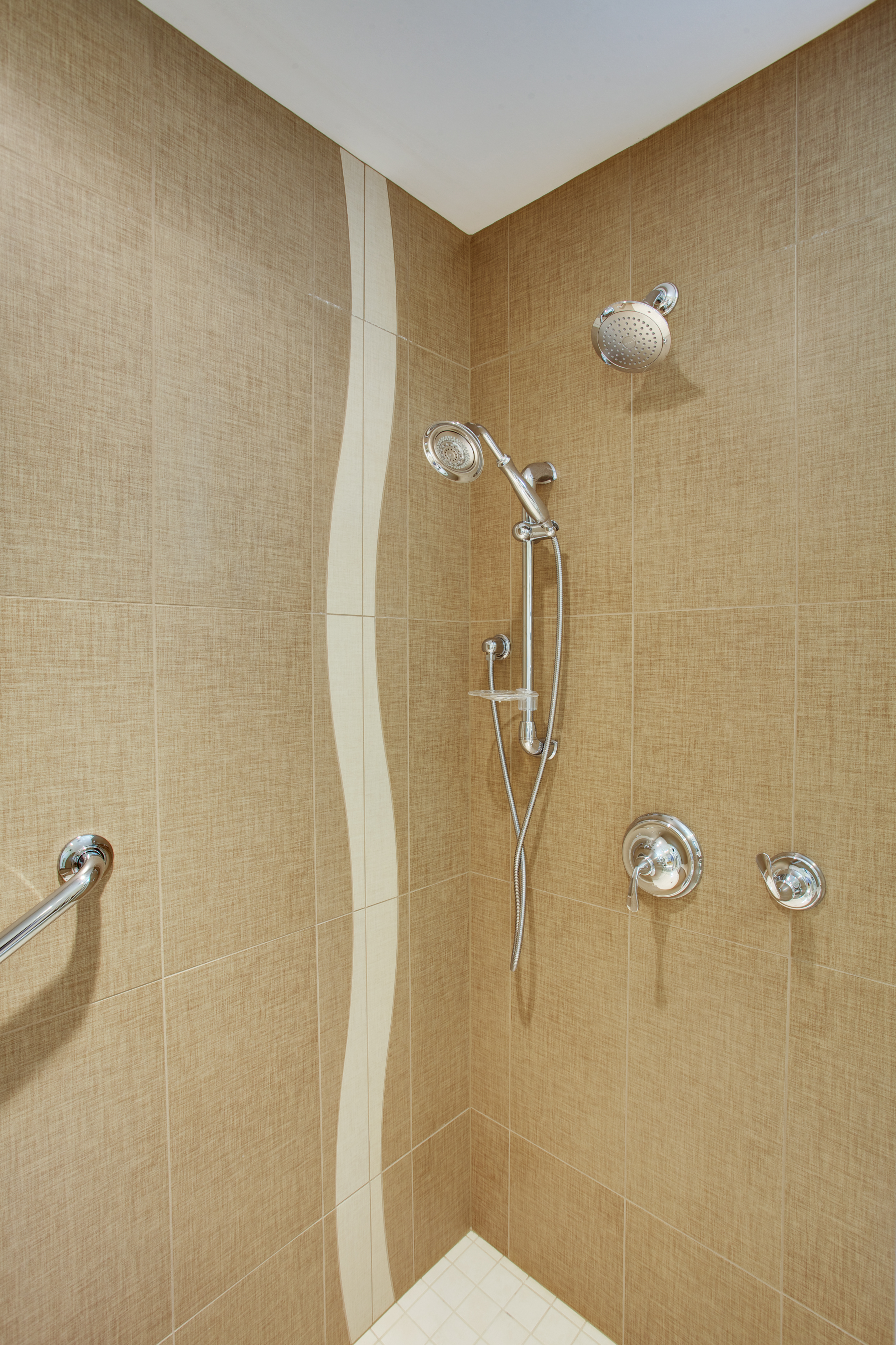 walk-in shower with brown and white tile and handle